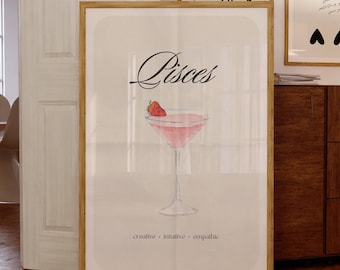 May include: A framed print with a watercolor illustration of a pink cocktail with a strawberry garnish. The text "Pisces" is written in cursive above the cocktail. Below the cocktail, the text "creative - intuitive - empathetic" is written in black.