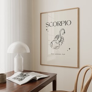 Pode incluir: Uma impress&atilde;o em preto e branco de um escorpi&atilde;o em linha com a palavra "SCORPIO" em texto preto acima. As palavras "corajoso, apaixonado, leal" est&atilde;o escritas em texto preto abaixo do escorpi&atilde;o. A impress&atilde;o est&aacute; emoldurada em uma moldura de madeira clara e est&aacute; pendurada em uma parede branca.
