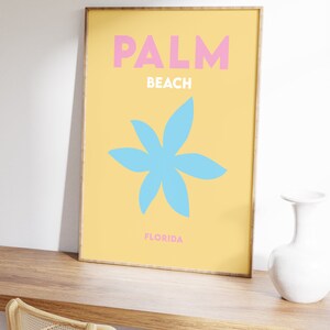 Palm beach florida text in pink and white on a yellow background with a blue flower illustration