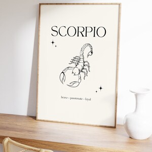 Pode incluir: Uma ilustra&ccedil;&atilde;o em preto e branco de um escorpi&atilde;o com a palavra "SCORPIO" em texto preto acima. As palavras "corajoso, apaixonado, leal" est&atilde;o escritas em texto preto abaixo do escorpi&atilde;o.