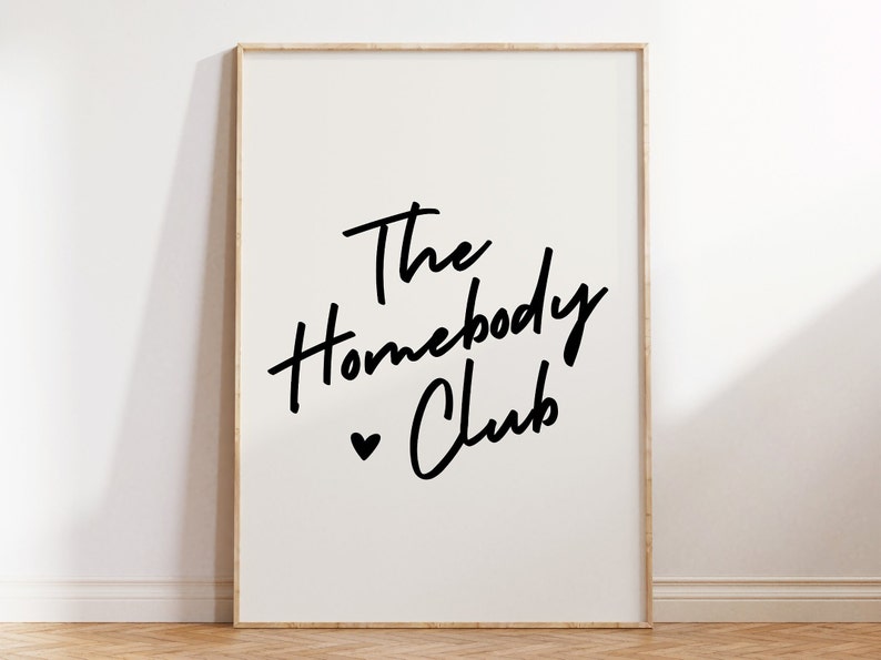 Cream background with The HomebodyClub written in black cursive 
 font with a black heart