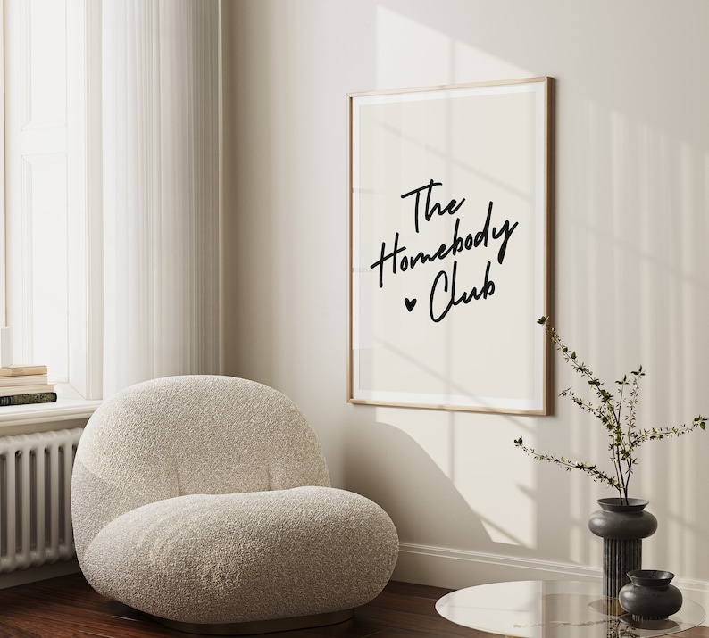 Cream background with The HomebodyClub written in black cursive 
 font with a black heart