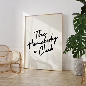 Cream background with The HomebodyClub written in black cursive 
 font with a black heart