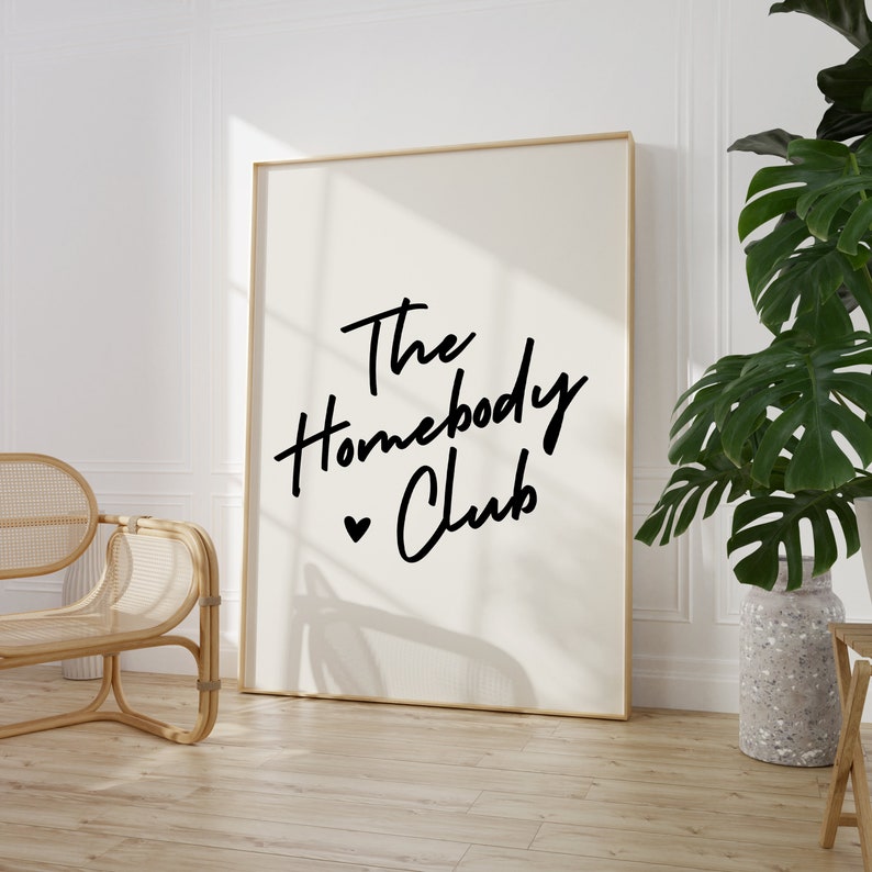 Cream background with The HomebodyClub written in black cursive 
 font with a black heart