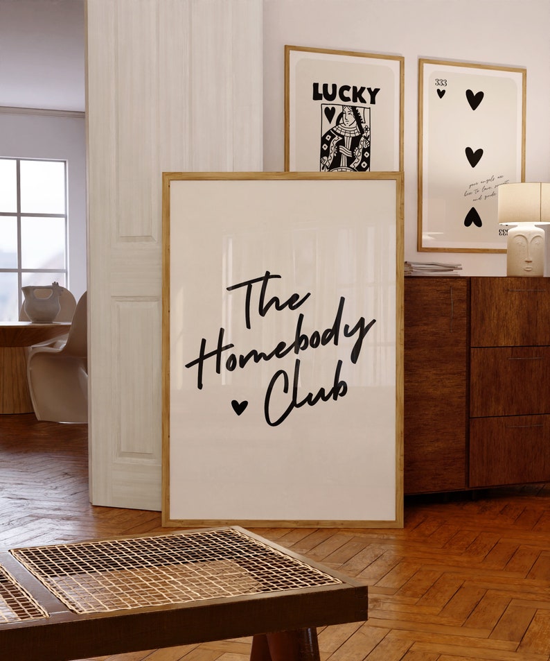 Cream background with The HomebodyClub written in black cursive 
 font with a black heart