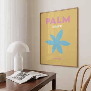 Palm beach florida text in pink and white on a yellow background with a blue flower illustration