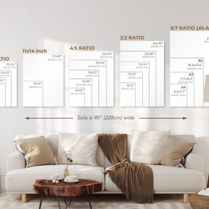 以下が含まれることがあります： ソファとフロアランプを背景に、アートワークの異なる印刷サイズを示す図。サイズはインチとセンチメートルで表示されています。「Sofa is 90" (228cm) wide」というテキストが図の下にあります。