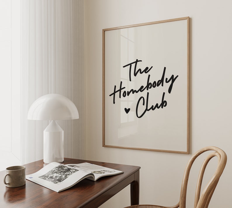 Cream background with The HomebodyClub written in black cursive 
 font with a black heart