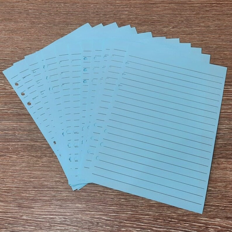 May include: A stack of light blue lined paper with holes punched along the left edge. The paper is designed for use in a binder.
