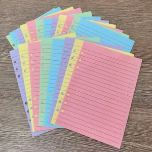 May include: A stack of colorful lined paper with punched holes for a binder. The paper is in shades of pink, yellow, blue, and green.