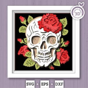 May include: A framed paper art piece showing a white skull decorated with red roses and green leaves on a black backdrop. The artwork is in a white square frame. The text "SVG + EPS + DXF" is at the bottom of the frame.
