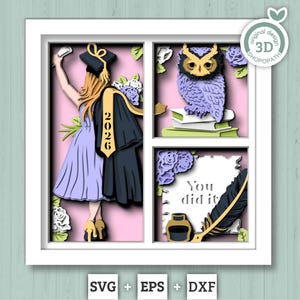 May include: A layered paper art piece in a white frame, featuring a graduation theme. It includes a graduate taking a selfie, an owl on books, and the text "You did it." The color scheme is pink, purple, and black.