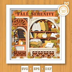 Op de afbeelding: Een 3D gelaagd papierkunstwerk in een witte lijst met de titel FALL SERENITY. Het toont een etalage met truien, pompoenen, boeken en herfstbladeren. De tekst bevat PUMPKIN SPICE LATTE, SWEATER WEATHER en COZY UP. Het ontwerp heeft warme oranje, gele en bruine tinten.