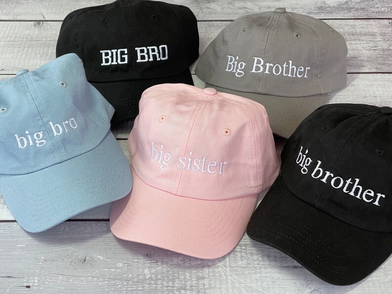 Puede incluir: Cinco gorras de b&eacute;isbol de diferentes colores con texto bordado. Las gorras son azules, rosas, grises, negras y negras. El texto en las gorras dice "big bro", "big sister", "Big Brother", "BIG BRO" y "big brother".