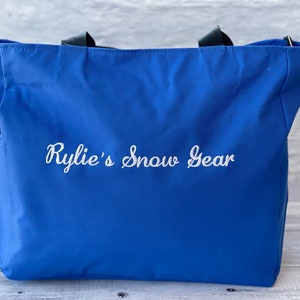 May include: A blue tote bag with black handles and a white embroidered design that says "Rylie's Snow Gear".