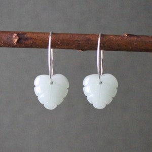Op de afbeelding: Een paar zilveren creolen met witte jade bladeren als hangers.