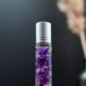 Peut inclure: Un flacon de verre transparent avec un bouchon argenté rempli de cristaux d'améthyste violets.