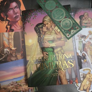 May include: A hardcover book titled Corruption of Chimeras by ES Drew featuring a couple in an embrace on the cover, accompanied by a green rectangular bookmark with the text As My Queen Demands and several illustrated character art prints.
