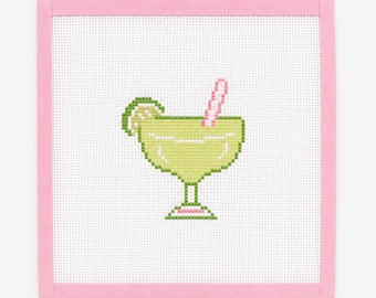 Peut inclure: Une toile de canevas carrée présentant un motif au point de croix d'un verre à margarita vert clair avec une tranche de citron vert et une paille rayée rose. Le motif est centré sur un tissu à grille blanc avec un bord en tissu rose uni.