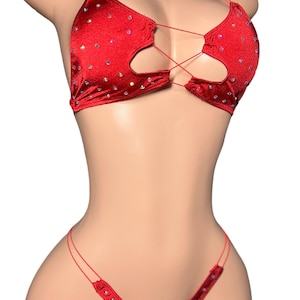 May include: A red satin bikini set with sparkling embellishments. The top has a halter neck and a unique cut-out design with criss-cross string detailing. The matching bottom has a V-shape front. This lingerie set is designed for a bold and glamorous look.
