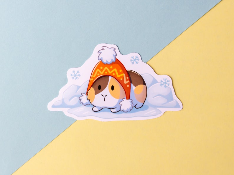 May include: A cartoon illustration of a guinea pig wearing a red and yellow knitted hat, nestled in a bed of white snow. The guinea pig has brown and white fur and is looking to the left.