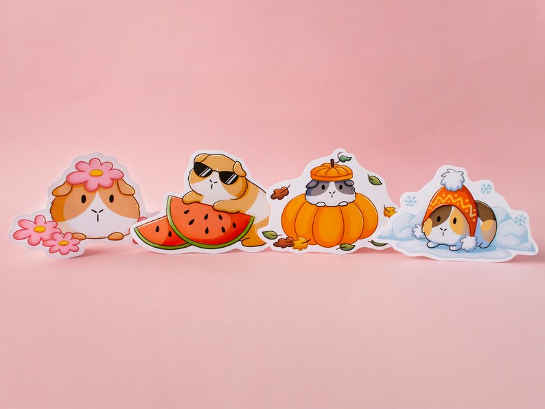 May include: Four illustrated stickers featuring guinea pigs in different seasonal outfits. The first sticker shows a guinea pig wearing a flower crown and holding a pink flower. The second sticker shows a guinea pig wearing sunglasses and holding a slice of watermelon. The third sticker shows a guinea pig wearing a pumpkin hat and sitting inside a pumpkin. The fourth sticker shows a guinea pig wearing a winter hat and scarf and sitting in the snow.