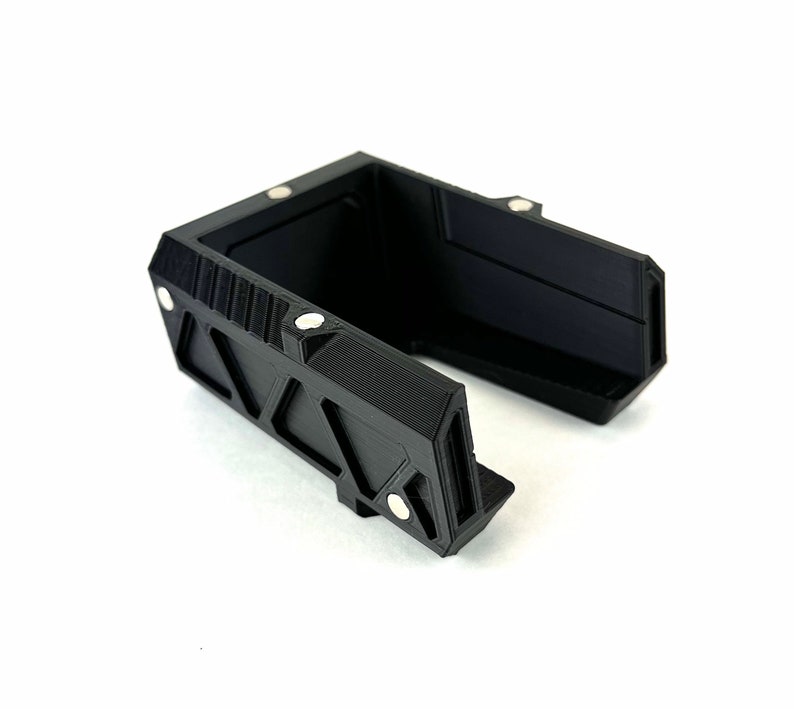 May include: Black plastic phone stand with a geometric design and magnetic closures.