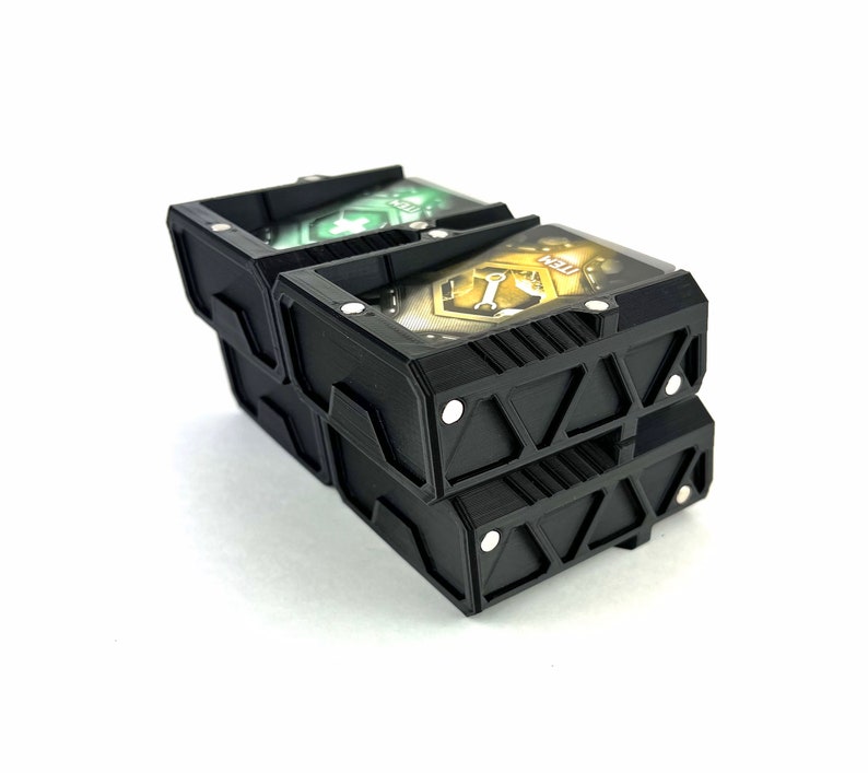 May include: Three black plastic card holders with magnetic closures. The top holder has a green and white card inside, the middle holder has a yellow and black card inside, and the bottom holder is empty.