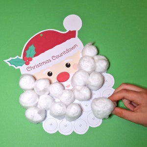 May include: A Christmas Countdown calendar shaped like Santa Claus, with a red hat and holly. The calendar has a series of numbered circles and cotton balls to mark the days. The text "Christmas Countdown" is printed on the calendar.