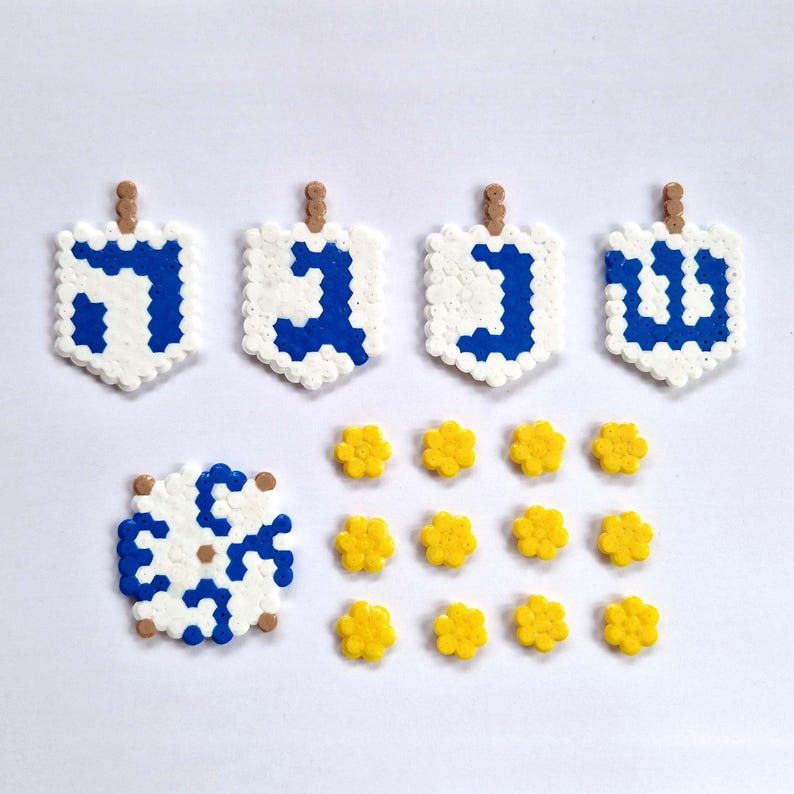 May include: Four blue and white dreidels with Hebrew letters, a white and blue snowflake, and twelve yellow flowers.