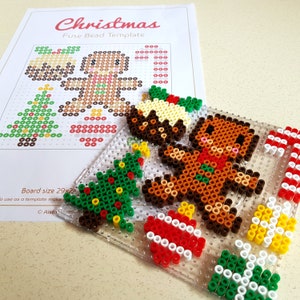 K&ouml;nnte beinhalten: Eine transparente Perlenplatte aus Kunststoff mit Weihnachtsmotiv. Die Platte zeigt einen Lebkuchenmann, einen Weihnachtsbaum, einen Zuckerstock und einen Weihnachtspudding. Die Platte ist 29 Zoll mal 29 Zoll gro&szlig;.