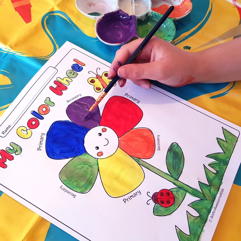 May include: A printable colour wheel activity sheet featuring a flower design. The flower has six petals, each labelled with "primary" or "secondary". The petals are coloured in with red, yellow, blue, orange, green, and purple paint. The centre of the flower has a yellow circle with a smiley face.