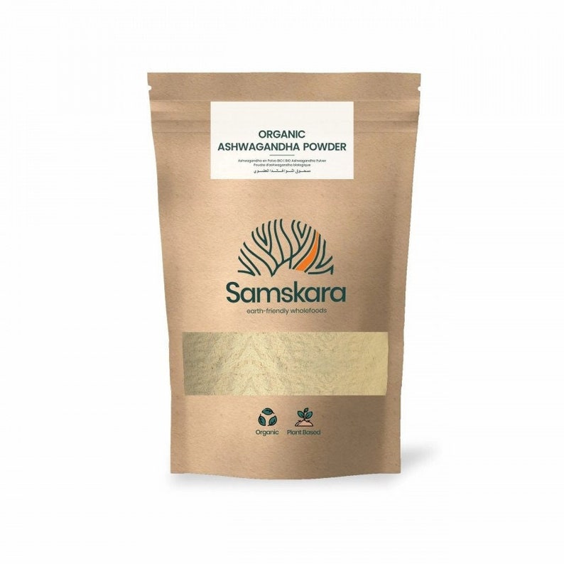 Puede incluir: Una bolsa de papel marr&oacute;n con una etiqueta blanca que dice "Organic Ashwagandha Powder" y el nombre de la marca "Samskara" en texto verde. La bolsa contiene un polvo marr&oacute;n claro y tiene una etiqueta verde y blanca en la parte inferior que dice "Organic Plant Based".