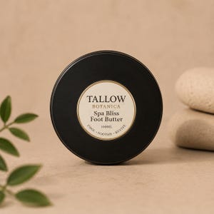 Könnte beinhalten: Ein schwarzer, kreisförmiger Behälter mit Tallow Botanica Spa Bliss Fußbutter. Das Etikett ist weiß mit goldenem Rand und Text. Der Text auf dem Etikett lautet "COOL. SOOTHE. REVIVE." Der Behälter enthält 100 ml Produkt.