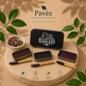 Op de afbeelding: Een vintage-geïnspireerde cosmeticaset. De afbeelding toont een zwarte mascara cake tin met de tekst "Daviz MASCARA CAKE", drie mascara cakes in bruin, zwart en paars, en bamboe applicators. Een kleine kom met gedroogde rozenknoppen is ook aanwezig.