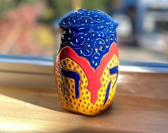 Ceramic tzedakah box in yellow, blue and red with decorative swirl