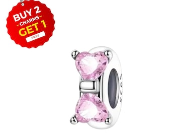May include: A silver charm with two pink heart-shaped gemstones. The charm has a white base and a silver band. A red tag with the text "BUY 2 CHARMS - GET 1 FREE" is attached to the charm.