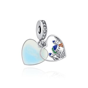 May include: Silver charm featuring two interlocking hearts. One heart is solid and has a white and blue iridescent finish. The other heart is open and features a colourful enamel cityscape.