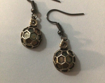 May include: A pair of silver earrings with a geometric hexagonal design. The earrings have black metal hooks.