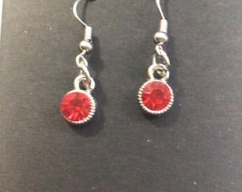 May include: A pair of silver dangle earrings with red round gemstones.