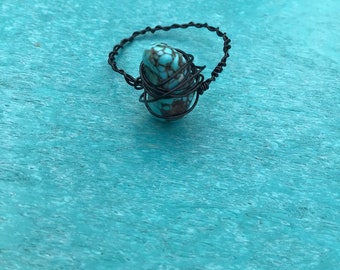 May include: A turquoise stone wrapped in black wire, creating a unique ring.