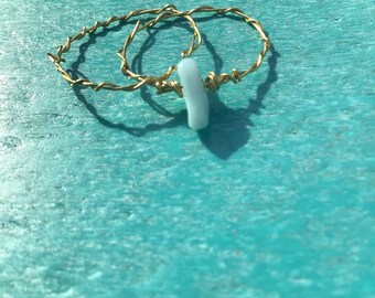 May include: Two gold wire wrapped rings with a light blue stone charm.