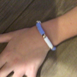 Puede incluir: Un brazalete azul y blanco con cuentas doradas.