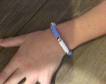 May include: A blue and white bracelet with gold beads.