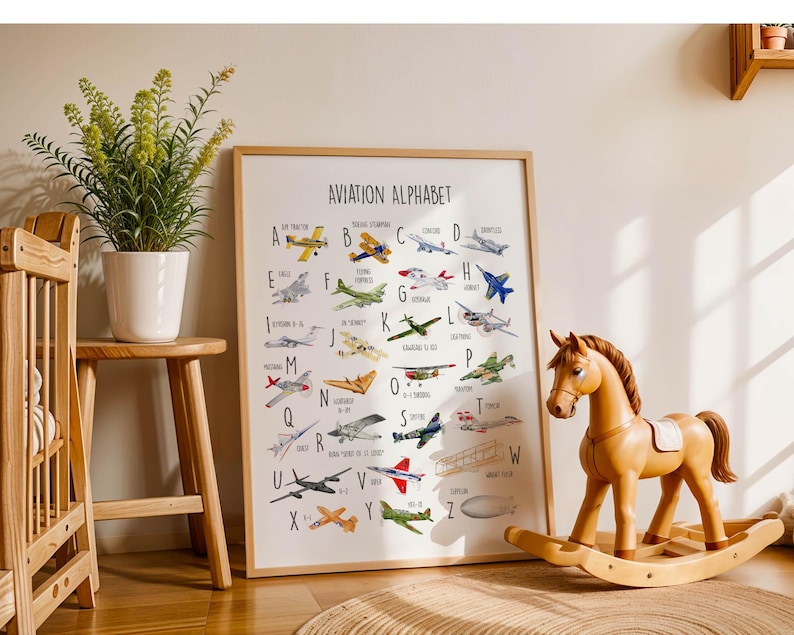 K&ouml;nnte beinhalten: Ein gerahmtes "Luftfahrt-Alphabet" Poster mit farbenfrohen Illustrationen verschiedener Flugzeuge, wobei jedes Flugzeug einem Buchstaben des Alphabets entspricht. Ein Schaukelpferd aus Holz und eine Topfpflanze sind ebenfalls im Bild.