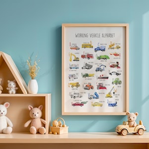 May include: A framed "Working Vehicle Alphabet" print with colorful illustrations of various vehicles. The print is displayed on a light wooden shelf, alongside teddy bears, a small toy car, and decorative items. The background is a light blue wall.