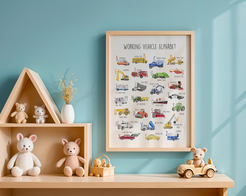 May include: A framed "Working Vehicle Alphabet" print with colorful illustrations of various vehicles. The print is displayed on a light wooden shelf, alongside teddy bears, a small toy car, and decorative items. The background is a light blue wall.