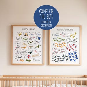 K&ouml;nnte beinhalten: Zwei gerahmte Lernposter zum Thema Luftfahrt. Eines zeigt das Alphabet mit Flugzeugillustrationen, das andere zeigt das Z&auml;hlen mit Flugzeugen. Die Poster sind in Holzrahmen und h&auml;ngen &uuml;ber einem Kinderbett. Der Text auf den Postern lautet "Aviation Alphabet" und "Counting with Planes".