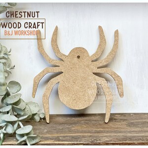May include: A light brown wooden spider cutout with eight legs and a small hole at the top. The text "CHESTNUT WOOD CRAFT B&J WORKSHOP" is in the upper left corner and lower right corner.