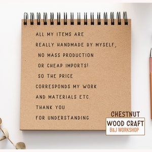May include: A tan spiral-bound notepad with handwritten text in black ink, highlighting handmade craftsmanship. A pen lies on the white surface. The notepad includes the text "CHESTNUT WOOD CRAFT B&J WORKSHOP".